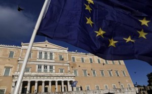 epa04814592 A protester waves a Greek flag (background) in front of the parliament during a rally demanding that Greece remains in the Eurozone, in Athens, Greece, 22 June 2015. The Eurozone's 19 national leaders hold an emergency summit in Brussels to discuss the crisis. Fears are mounting that Greece is about to run out of money, with the country facing a 1.6-billion-euro IMF repayment deadline on June 30. EPA/YANNIS KOLESIDIS