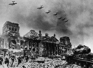 In this composite image by Yevgeny A. Khaldei (March 23, 1917 - October 6, 1997), the renowned photographer has seven Petlyakov Pe-2 dive bombers overflying the Reichstag while Red Army soldiers rush the building supported by a Josef Stalin IS-2 tank. There are at least four separate images in this composite. The Reichstag is one; the original has a destroyed bus in the lower left, which was covered by the onrushing Red Army squad. The squad is likely a staged reenactment, possibly taken on May 4 when photographer Ivan M. Shagin (1904-1982) also photographed the reenactment. The Petlyakov Pe-2 aircraft appear to be the same aircraft duplicated seven times. The IS-2 tank is significant, not only because it is named after Stalin; IS-2 tanks, attached as one heavy tank brigade to each of the Soviet Fronts (Army Group). Later enough IS-2s were produced so that each tank corps had an IS-2 regiment with twenty-one tanks. The IS-2 was reserved for storming fortifications, in concert with combat engineers. It could engage German Tiger I and II tanks, although the Tiger's 88mm (3.46 inch) gun could outrange the IS-2's 122mm (4.8 inch) gun. The composite photo was often used by Soviet photographers, who did not have any ethical issues with manipulating images. Khaldei himself made several other composite images during the war.