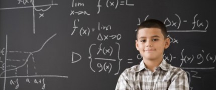 Hispanic boy smiling in front of math formula on blackboard